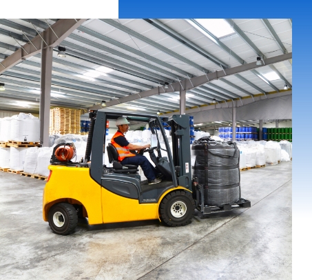 Forklift on warehouse floor carrying items equipped with propane tank