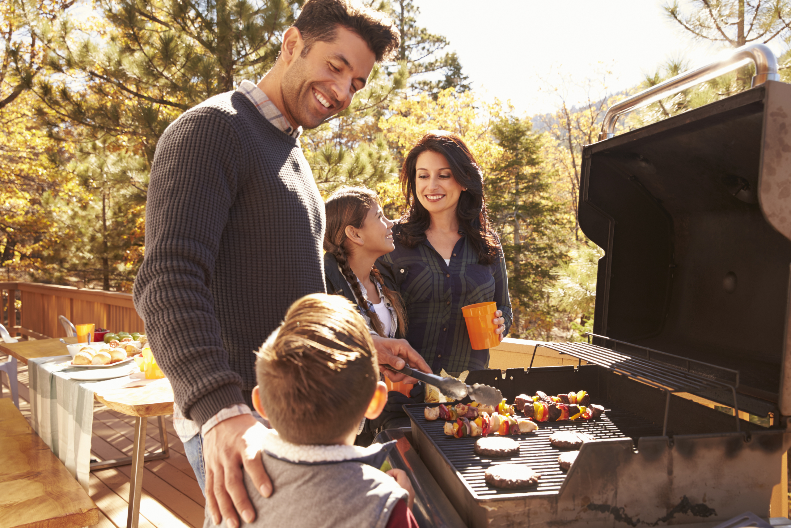 A family cooks on a grill outside