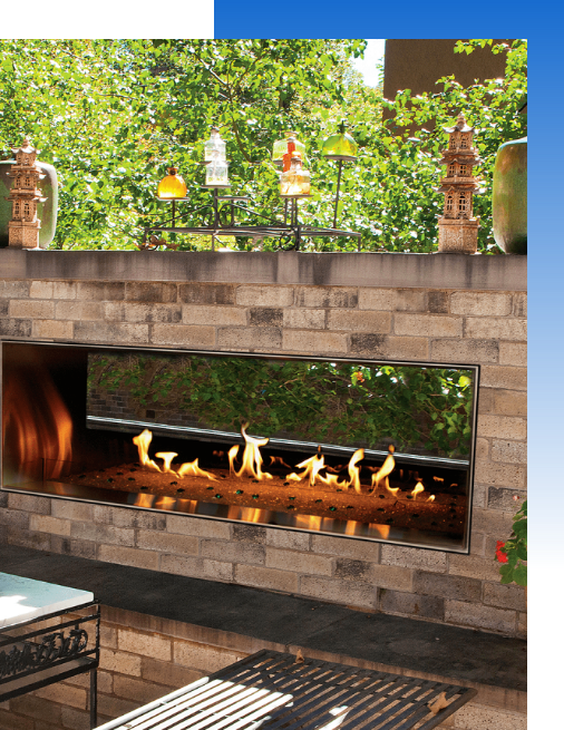 A stone outdoor fireplace in front of bushes